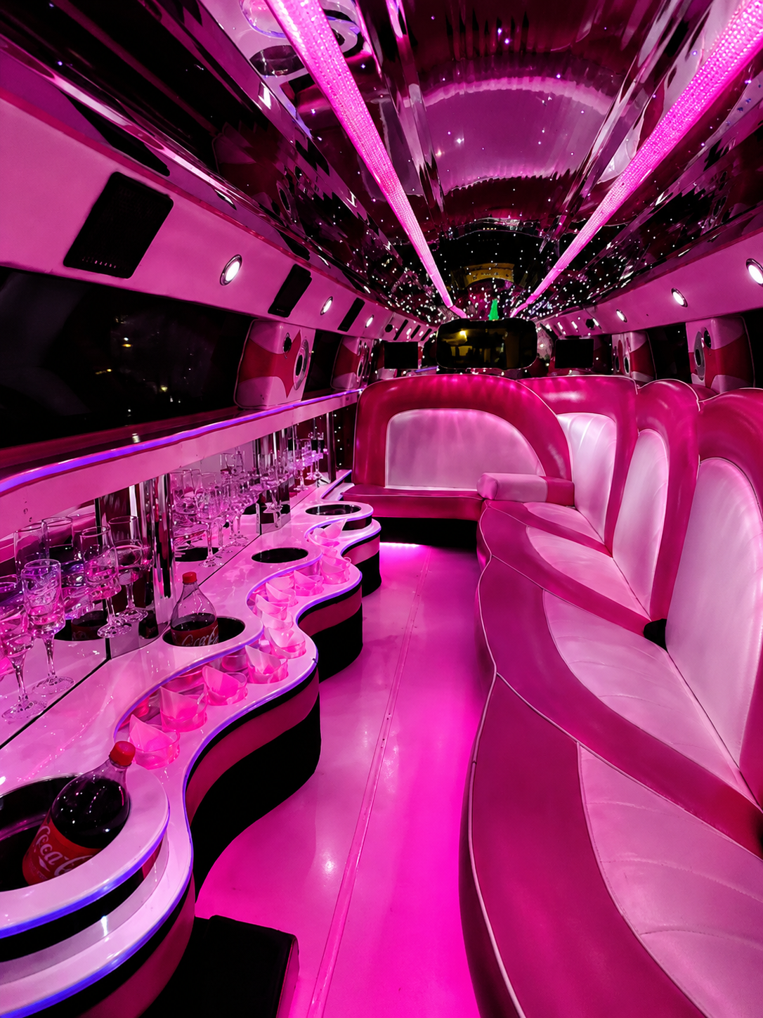 Interior rosa iluminado da limousine visto em direção aos bancos
