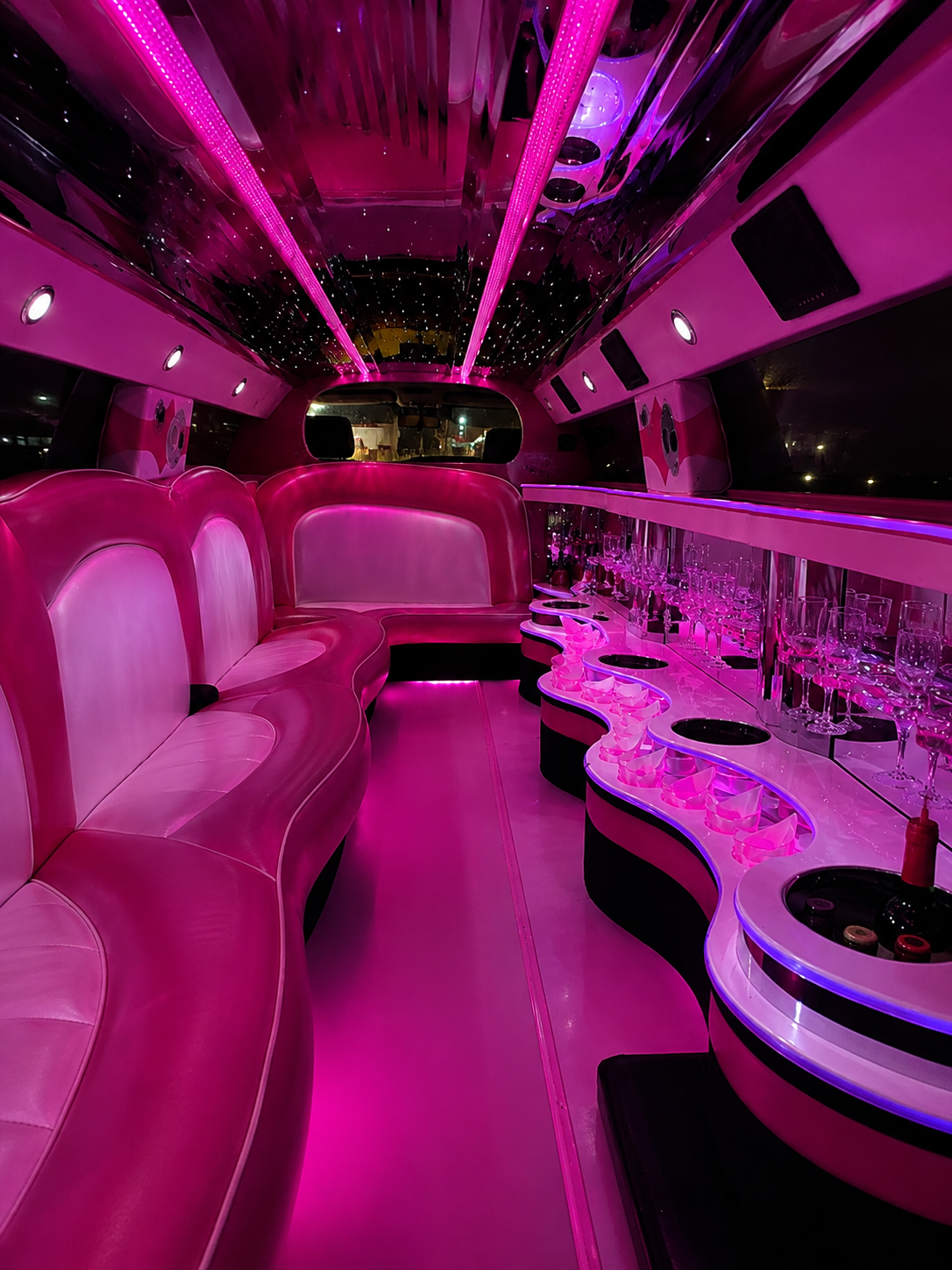 Interior rosa da limousine com bancos, bar e teto estrelado